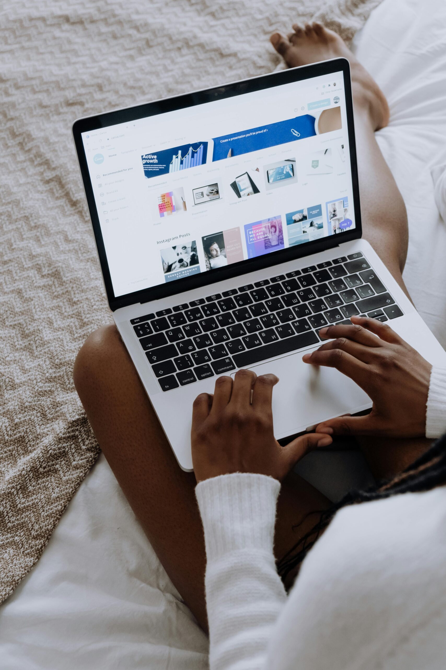 A woman browsing digital designs on a laptop while sitting comfortably at home.