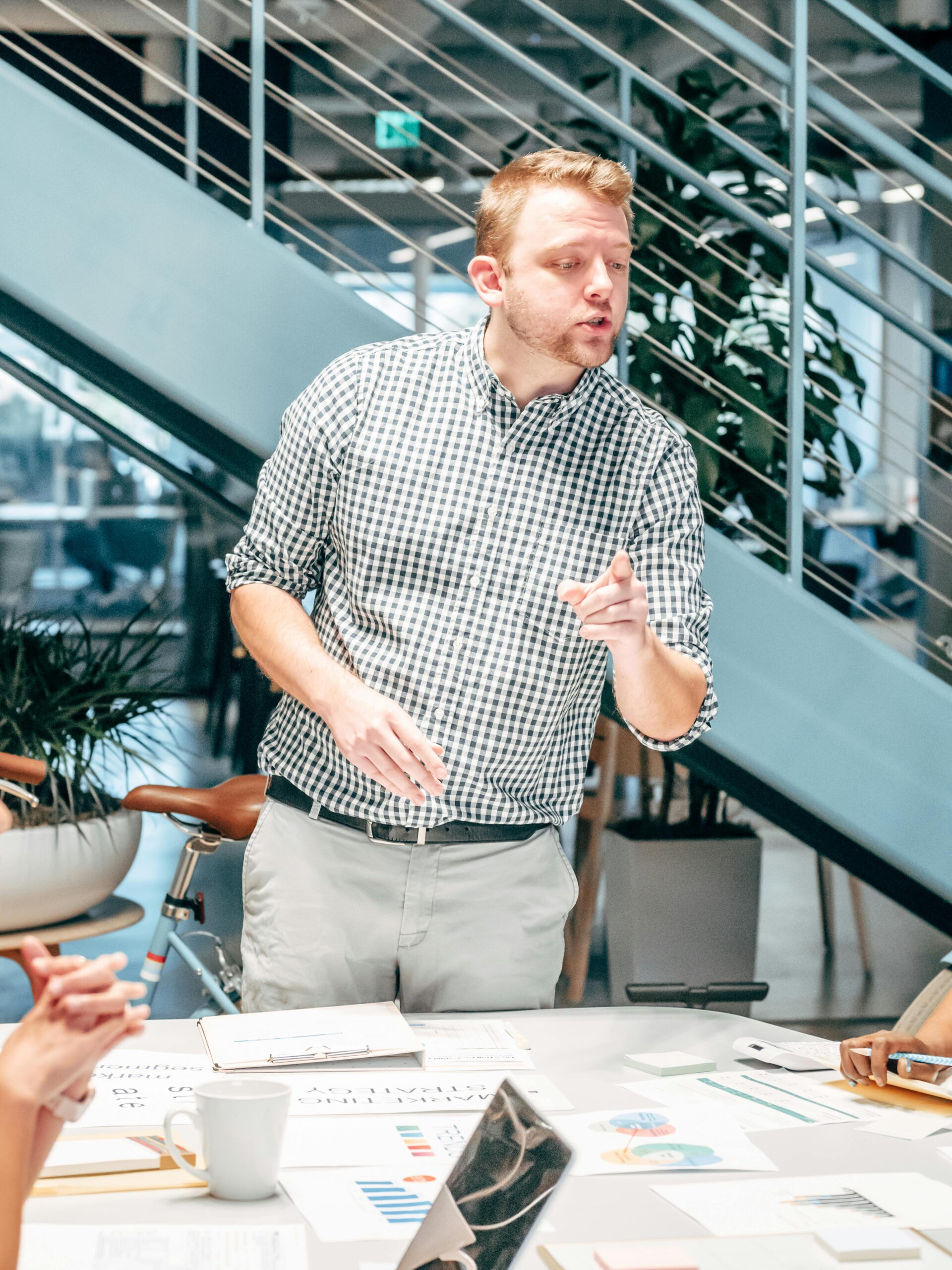 A man in a checkered shirt discussing ideas in a modern office workspace.